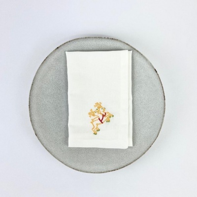 Guardanapo branco com bordado de cervo sobre um prato cinzento