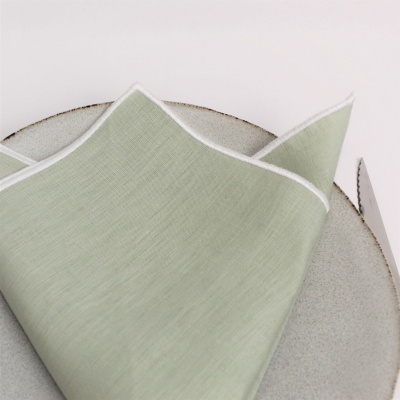 Guardanapo verde claro sobre prato cinza com faca ao lado