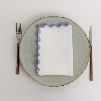 Prato cinza com guardanapo branco bordado azul e talheres com cabo de madeira