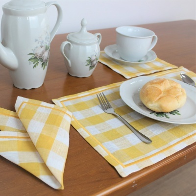 Conjunto de chá em porcelana com decoração floral sobre pano amarelo às riscas na mesa