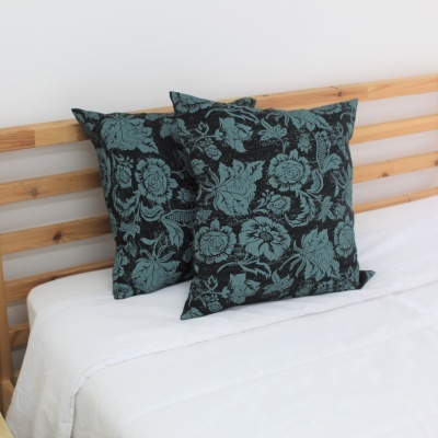 Almofadas decorativas verdes e pretas com padrão floral em cama branca e cabeceira de madeira