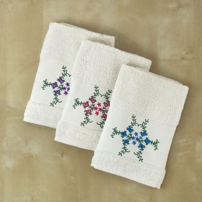 Três toalhas de banho brancas com bordados florais coloridos