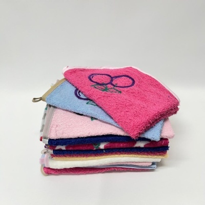 Toalhas de rosto coloridas empilhadas, a da frente rosa com bordado de cerejas.