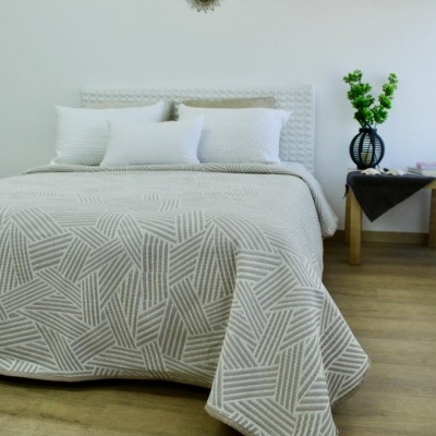 Cama com colcha branca de padrão geométrico cinzento, almofadas brancas e decoração minimalista