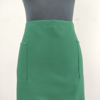 Saia verde com bolsos frontais em tecido liso exibida em manequim