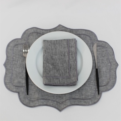Conjunto de mesa com guardanapo e individual cinzentos, prato branco, garfo e faca com cabo preto
