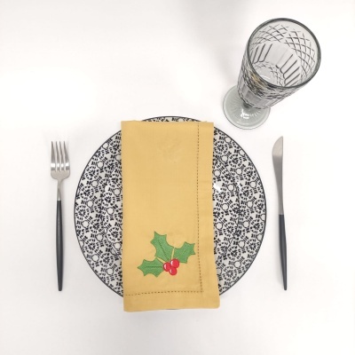 Conjunto de talheres, prato com padrão floral azul e guardanapo amarelo com azevinho
