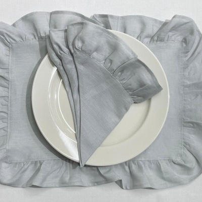 Conjunto de prato branco, guardanapo cinzento e individual cinzento sobre superfície branca