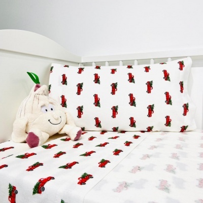 Roupas de cama infantis com padrão de carros vermelhos e peluche creme num berço branco