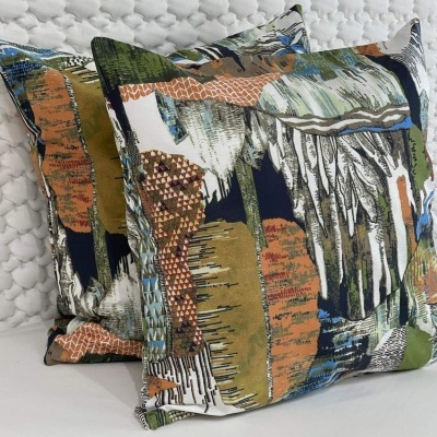 Duas almofadas quadradas decorativas com padrão abstrato colorido sobre fundo branco