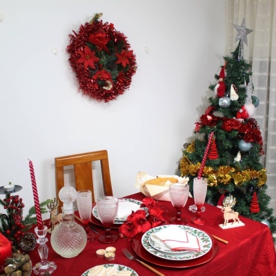 Mesa festiva de Natal com decoração vermelha e árvore de Natal decorada em sala com parede branca