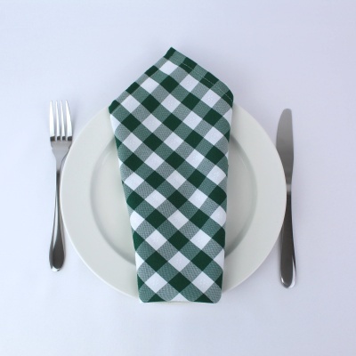 Guardanapo verde e branco quadrado sobre prato branco com talheres ao lado