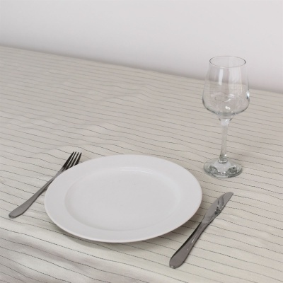 Conjunto de prato, garfo, faca e taça sobre toalha de mesa riscada