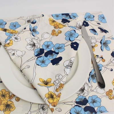 Guardanapo floral azul, amarelo e preto em prato branco com faca