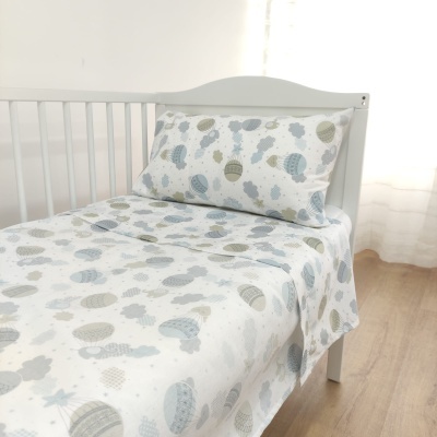 Cama de criança branca com roupa de cama estampada com balões e nuvens em tons pastel