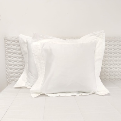 Almofadas brancas com fronhas texturizadas sobre cama branca