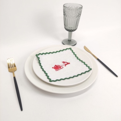 Conjunto de louça com pratos brancos, guardanapo decorado, talheres preto e dourado e copo de vidro cinzento texturizado