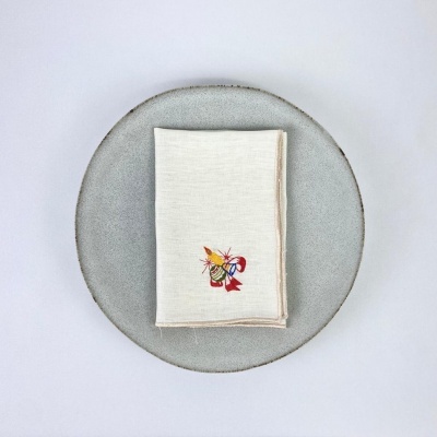 Guardanapo branco com bordado colorido sobre prato cinza redondo