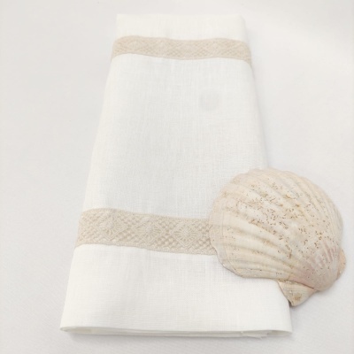 Toalha branca de linho com bordas bege e concha marinha junto a ela