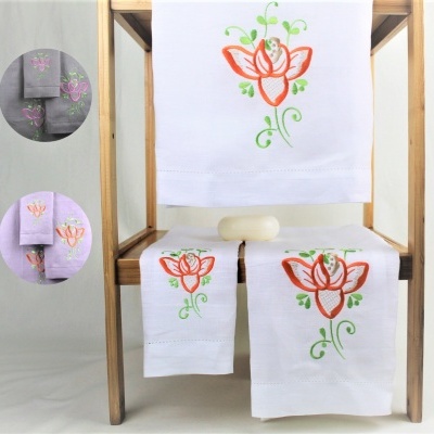 Toalhas brancas bordadas com flores coloridas sobre estrutura de madeira