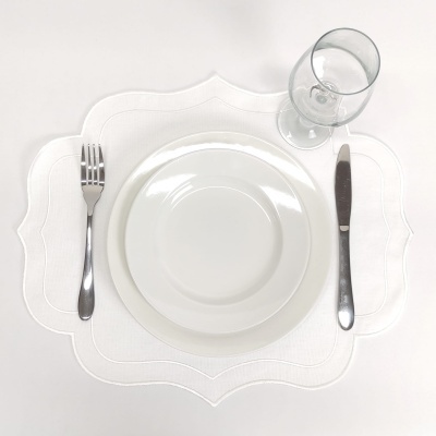 Conjunto de mesa com prato branco, talheres prateados, copo de vidro e individual branco