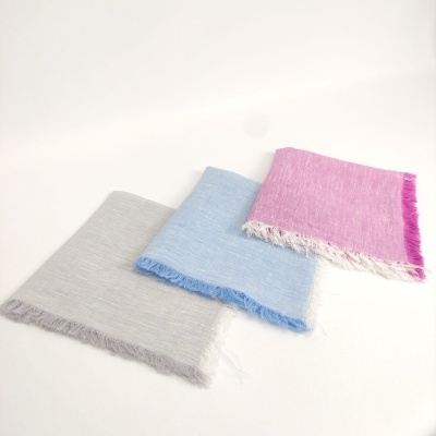 Três panos de algodão com franjas em cinza claro, azul claro e rosa sobre fundo branco