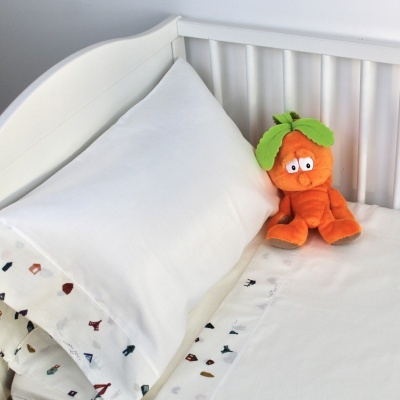 Travesseiro branco com fronha estampada e boneco laranja num berço branco