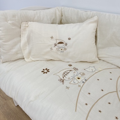 Roupas de cama infantis bege e branco com bordados de personagens e flores