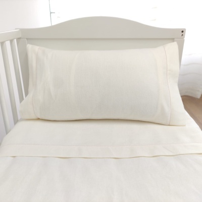 Almofada e lençol creme com acabamento em pontos decorativos em berço branco