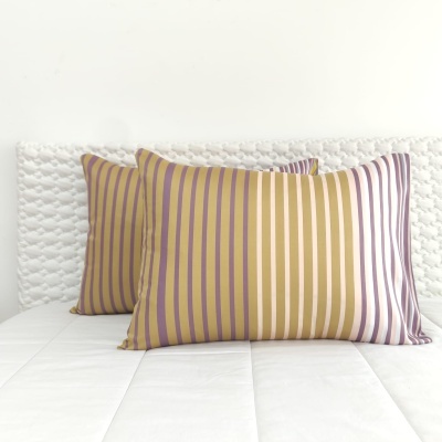 Duas almofadas com riscas verticais coloridas sobre colchão branco e cabeceira texturizada