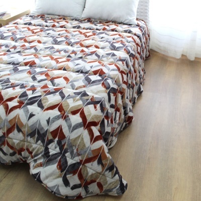 Edredão com padrão geométrico colorido numa cama com almofadas brancas