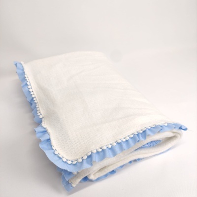 Manta branca com franja azul clara e pompons brancos