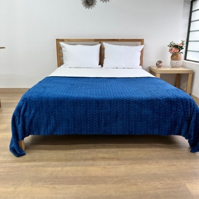 Cama com manta azul e almofadas brancas numa decoração simples e clara