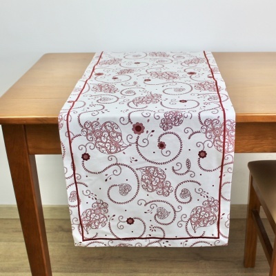 Caminho de mesa branco com padrão bordô decorativo sobre mesa de madeira clara