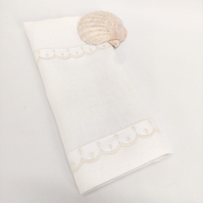 Guardanapo branco com bordado bege e concha rosa claro em fundo branco