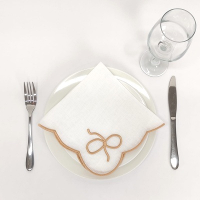 Prato branco com guardanapo de tecido branco bordado, talheres e taça de vidro