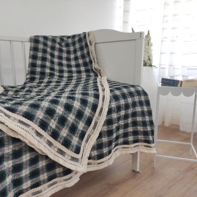 Cobertor quadriculado azul escuro, branco e bege com borda de crochê na cama branca