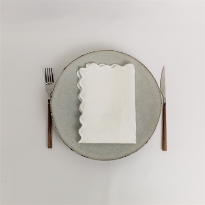 Conjunto de jantar com prato cinza, guardanapo branco, garfo e faca com cabos de madeira