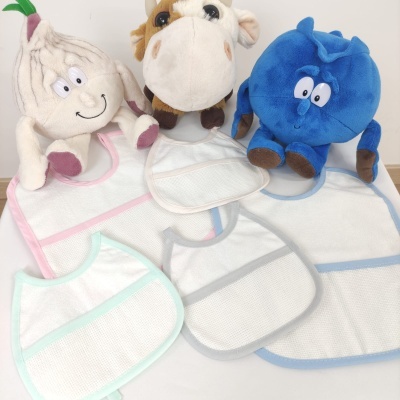 Babetes brancos com bordas coloridas e três peluches coloridos sobre superfície clara