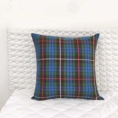 Almofada com padrão tartan sobre cama branca acolchoada