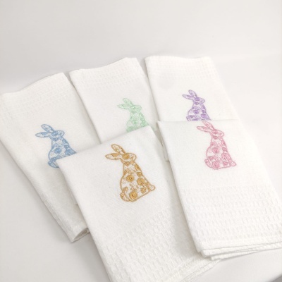 Cinco toalhas brancas com bordados de coelhos coloridos em diferentes posições