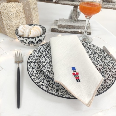 Conjunto de pratos preto e branco com guardanapo bordado e copo com bebida laranja