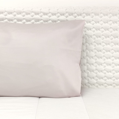 Travesseiro cinza claro e colchão branco com capa texturizada em losangos.