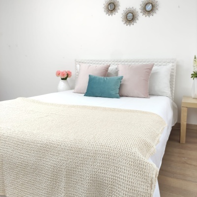 Cama com mantas e almofadas em cores suaves e decoração minimalista branca