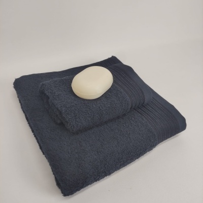 Toalhas azuis escuras dobradas com uma barra de sabão branca oval