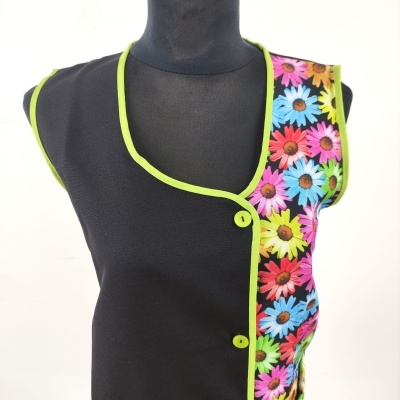 Colete preto com padrão floral colorido e botões verdes num manequim preto