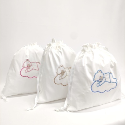 Sacos de tecido branco com ursinhos bordados a dormir numa nuvem em rosa, castanho e azul