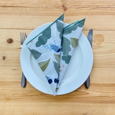 Mesa posta com prato branco, guardanapo estampado dobrado, garfo e faca sobre madeira clara