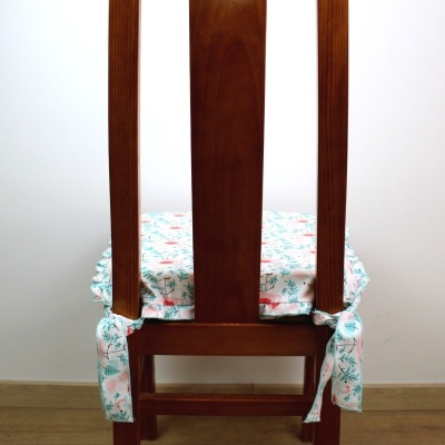 Cadeira de madeira com capa almofadada branca com padrão floral azul e salmão