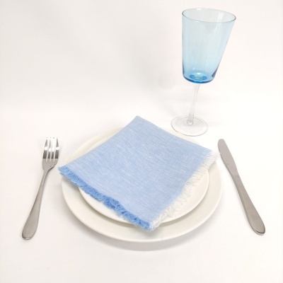Mesa posta com prato branco, guardanapo azul claro, copo azul, garfo e faca